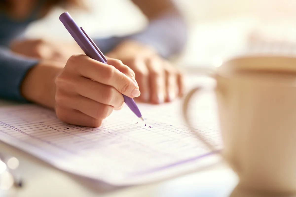 Close-up of hands ticking boxes on a printed Uplyft Capital loan payment schedule
